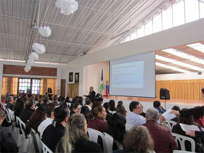 Padres de familia reunidos en el salón comunal de un colegio durante una charla