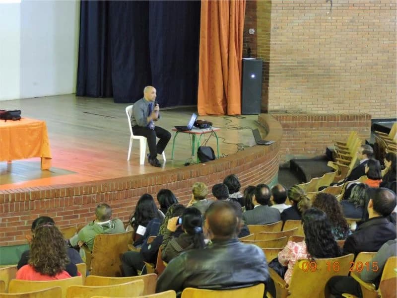 Conferencia en un teatro escolar con el público ocupando toda la platea