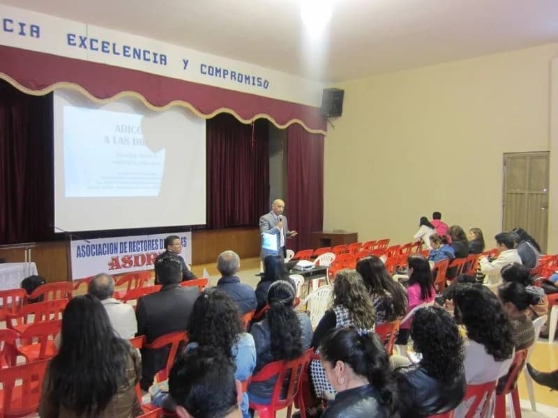 Conferencia en la tarima de un colegio con pancarta institucional