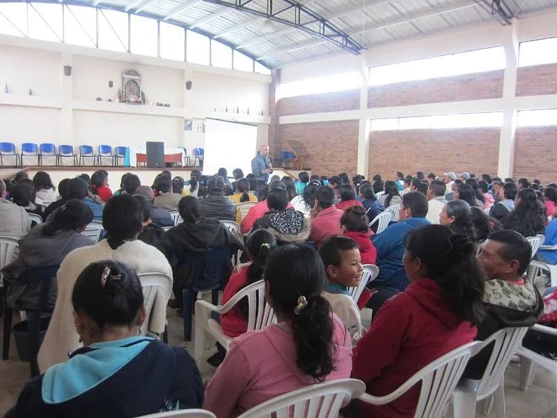 Padres de familia atentos al conferencista en un salón comunal